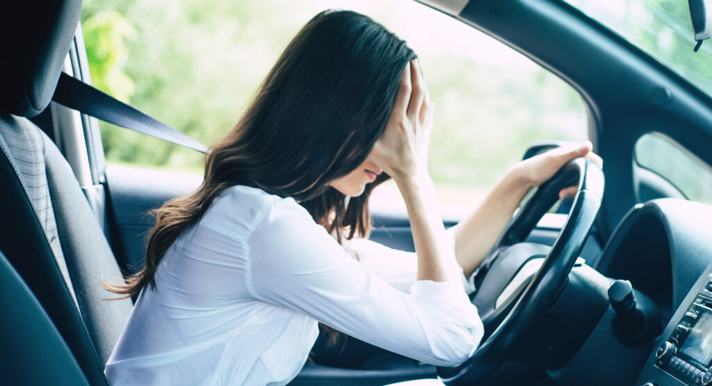 Woman stressed in car holding her head