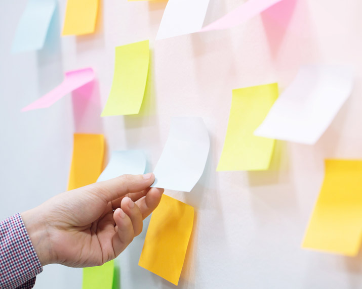 hand placing post it notes on a board having troubles focusing on a single task