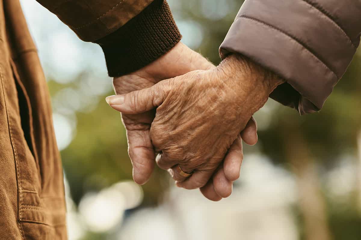 closeup of two old people holding hands