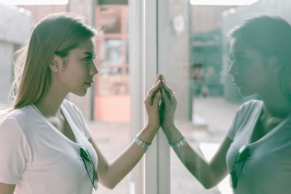 Woman looking at her own reflection in glass