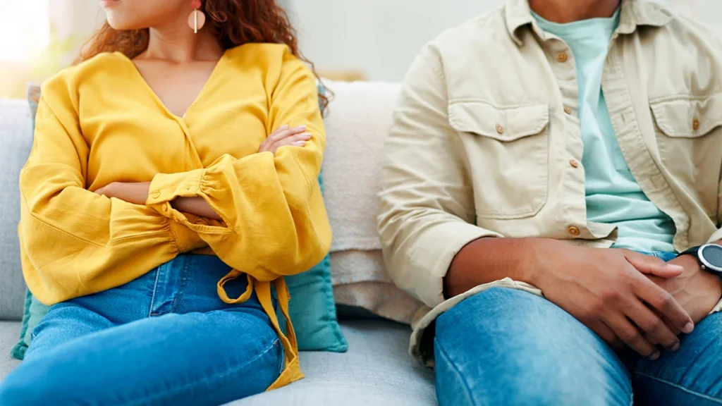 Couple sitting in a couch, the woman has crossed arms
